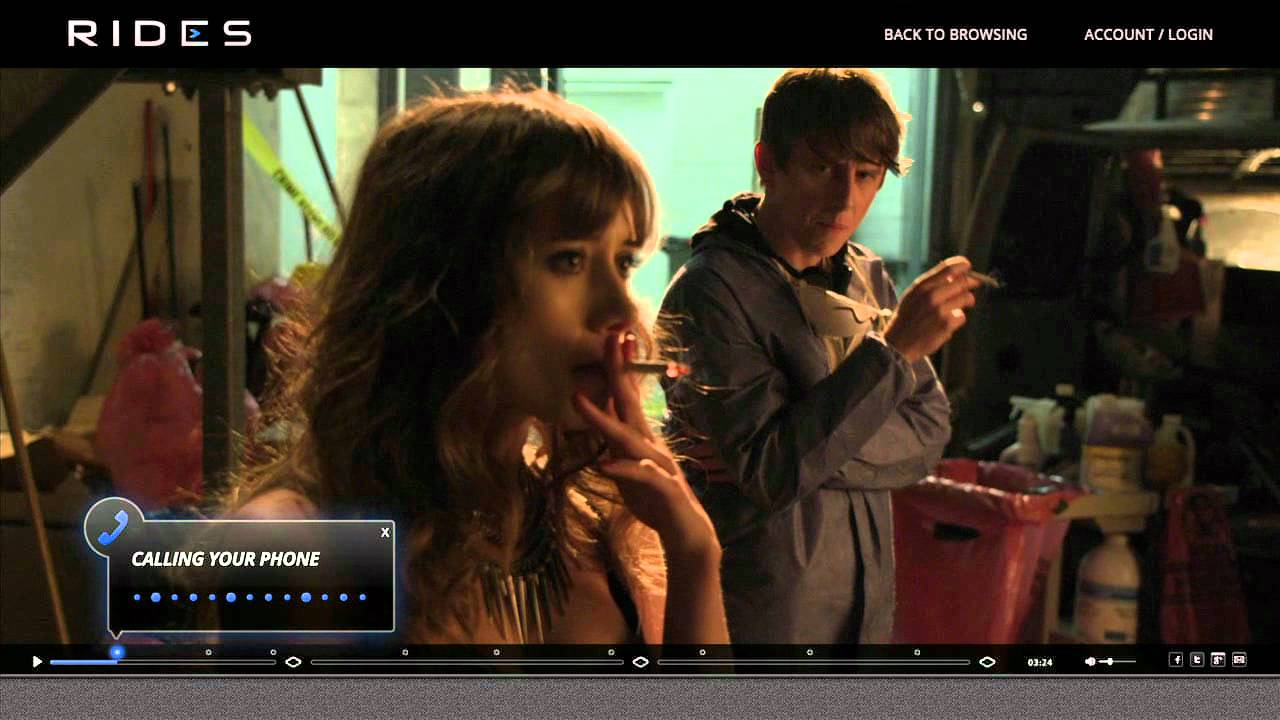 A scene from Episode 1 of Dirty Work showing Pete (Hank Harris) smoking with Bambi (Olesya Rulin), on the Rides.TV interactive platform. The interface shows an overlay prompt reading 'Calling Your Phone,' illustrating a viewer participation mechanic.
