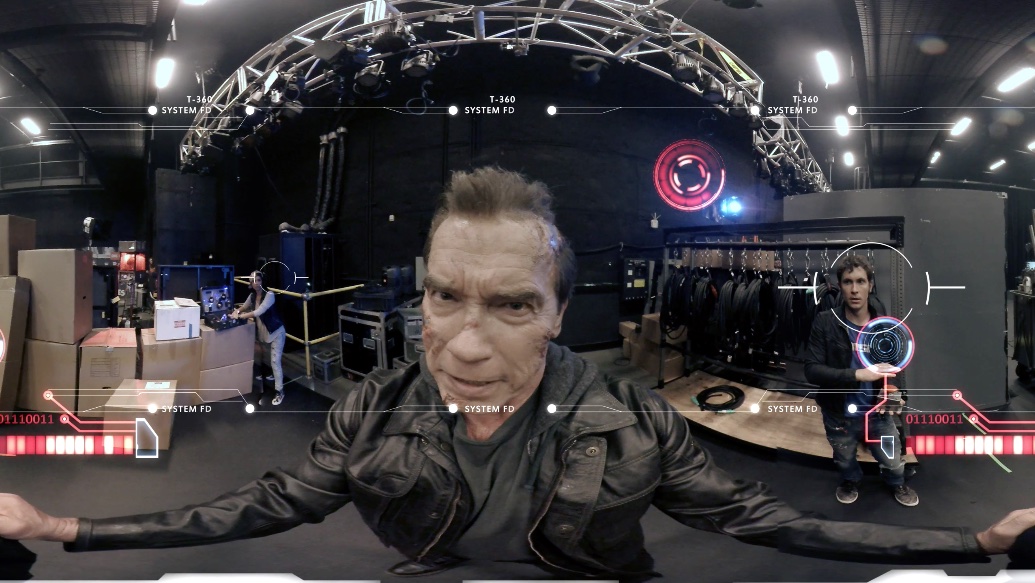 A 360-degree video still from the Terminator Genisys: The YouTube Chronicles VR episode showing Arnold Schwarzenegger as the T-800, alongside Lilly Singh and Toby Turner, surrounded by Skynet interface overlays and targeting reticles.