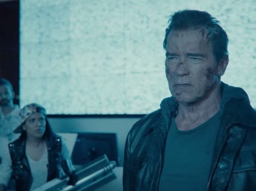 Screenshot from the third episode of the series, showing Arnold Schwarzenegger as the T-800 against a video screen showing static. Next to him, Lilly Singh carries an oversized weapon.
